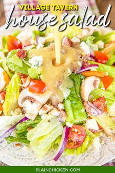 a salad with dressing being drizzled over it and the words village tavern house salad