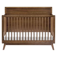 a wooden crib with white sheets on the bottom and sides, against a white background