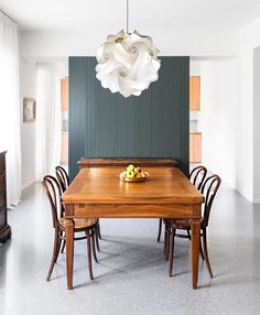 a dining room table and chairs with a bowl of fruit on the table in front of it