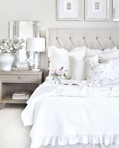 a bed with white sheets and pillows in a bedroom next to two framed pictures on the wall