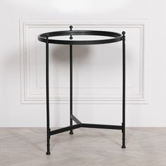 a round table with black metal legs and a white wall in the backround