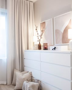 a white dresser sitting next to a window covered in curtains