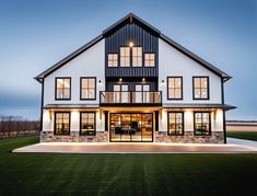 a large white house with lots of windows and lights on it's front porch