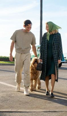 a man and woman walking their dog down the street