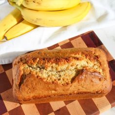 a loaf of bread sitting on top of a wooden cutting board next to some bananas