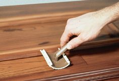 a person with a brush on top of a wooden floor next to a piece of furniture