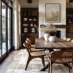 the dining room table is surrounded by wicker chairs and vases with flowers in them