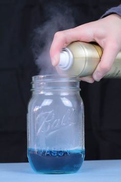 a person pouring blue liquid into a glass jar