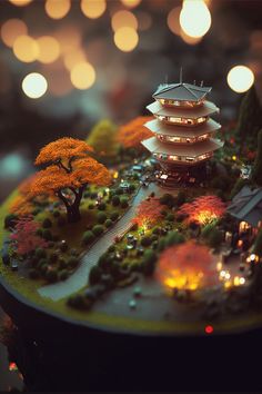 a miniature model of a pagoda with trees and lights in the background