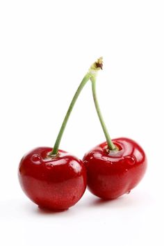 two cherries are sitting side by side on a white surface