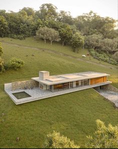 an aerial view of a house in the middle of a grassy field with trees around it