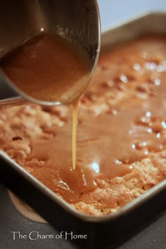 a person pouring sauce on top of a cake in a pan