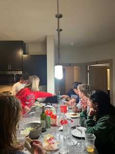 a group of people sitting around a kitchen table eating food and drinking water from cups