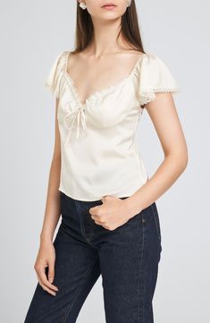 Romantic lace trims the neckline and fluttery sleeves of this slinky satin top that adds sweet, charming style to your next OOTD. 11" center front length (size Medium) Sweetheart neck Short sleeves Partially lined 100% polyester Hand wash, dry flat Imported Elegant Fitted Top With Butterfly Sleeves, Elegant Fitted Tops With Butterfly Sleeves, Flirty Fitted Satin Tops, Spring Satin Short Sleeve Tops, Feminine Satin Top With Lace Trim, Feminine Satin Lace Top, Satin Ruffle Tops, Fitted Cream Satin Top, Cream Fitted Satin Top