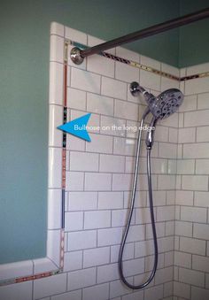 a shower head with an arrow pointing to the right in front of it on a tiled wall