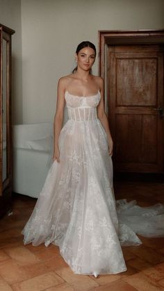 a woman in a white wedding dress standing on a tile floor next to a bed