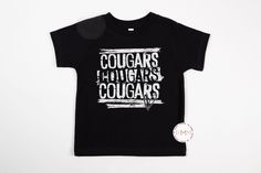 Cougars Shirt. Graphic design in white. ♥ Infant, Toddler and Youth unisex t-shirts are Bella Canvas brand ♥ All items are made to order ♥ Any prop items (hats, shoes, blankets, etc.) in photos are not included. --------------------------------------------- PROCESSING TIME: 3-5 business days (M-F) before an item ships. If you need something sooner, please send a message before purchase. SIZING:  Size charts are available in the photos.  Any questions - send a message. CARE INSTRUCTIONS: Wash ins Black Tops With Name Print For Fan Gear, Black Cotton Shirt For School Spirit, School Spirit Sports Shirt In Cotton, Black Shirt With Team Name For School Spirit, Black Shirt With Text Print For Game Day, White Sporty Shirt With Name Print, Sporty White Shirt With Name Print, School Spirit Black Shirt With Team Name, Black School Spirit Shirt With Team Name