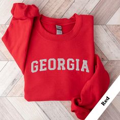 Georgia Sweatshirt, Georgia Vacation Sweater, USA Sweater Georgia, Georgia Sweatshirt, Georgia Trip, Vacation to Georgia Sweater * 50% cotton, 50% polyester * Pre-shrunk * Classic fit * 1x1 athletic rib knit collar with spandex * Air-jet spun yarn with a soft feel and reduced pilling * Double-needle stitched collar, shoulders, armholes, cuffs, and hem This product is made especially for you as soon as you place an order, which is why it takes us a bit longer to deliver it to you. Making products College Red Tops With Embroidered Text, Red College Top With Embroidered Text, Red College Tops With Embroidered Text, Red Embroidered Text College Tops, Collegiate Embroidered Tops For College, Winter Fan Apparel Tops With Embroidered Logo, Winter Tops With Embroidered Graphics For College, Collegiate Embroidered Winter Tops, Collegiate Tops With Embroidered Graphics For Winter