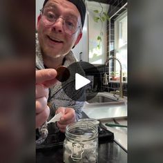 a man holding a spoon over a jar filled with liquid