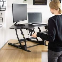 a woman standing in front of a computer desk