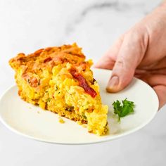 a person holding a plate with a slice of quiche on it and garnished with parsley