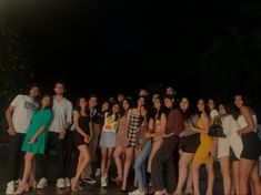 a group of young people standing next to each other in front of a building at night