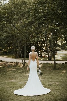 the back of a bride's dress is shown in front of trees and grass