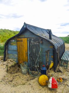 an outhouse with a blue tarp on the roof and several different items around it