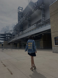 a woman is standing in front of an empty stadium with her back to the camera