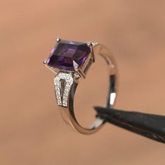 It is a natural amethyst ring. The main stone is 7 mm* 9 mm emerald cut.weight about 2.21 carats.The basic metal is sterling silver and plated with rhodium.To change the metal to a solid gold (white/rose) or platinum is also available, please ask for a quotation if you want.You can also go to my shop Home for more elegant rings: https://www.etsy.com/shop/godjewelry?ref=hdr_shop_menu Amethyst is February birthstone More amethyst rings:https://www.etsy.com/shop/godjewelry?ref=seller-platform-mcnav Elegant Amethyst Birthstone Diamond Ring, Elegant Purple Solitaire Birthstone Ring, Elegant White Gold Amethyst Birthstone Ring, Elegant Purple Gemstone Birthstone Ring, Classic Emerald Cut Amethyst Ring With Center Stone, Elegant Purple 14k White Gold Jewelry, Purple Amethyst Ring With Rectangular Stone For Anniversary, Elegant Amethyst Ring With Rectangular Stone For Anniversary, Elegant Amethyst Birthstone Ring With Prong Setting