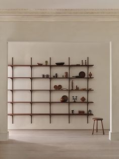 an empty room with shelves and tables on the wall, in front of a white wall