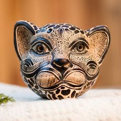 a ceramic cat figurine sitting on top of a white cloth covered tablecloth