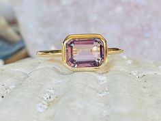 a pink tourmaline ring sitting on top of a white rock