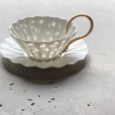 a white cup with a gold handle sitting on top of a saucer in the shape of an umbrella