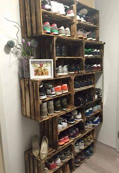 a wooden shoe rack filled with lots of pairs of shoes next to a white wall