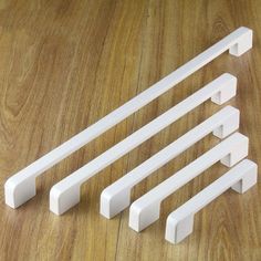 five white plastic handles on a wooden floor with one missing the handle and four remaining