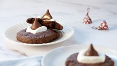 chocolate cookies with marshmallows and whipped cream on top are sitting on plates