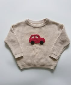 a knitted sweater with a red car on the front and black wheels on the back