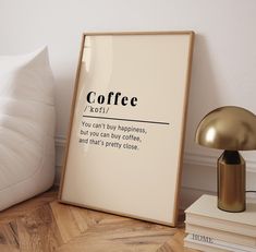 there is a framed poster on the floor next to books and a lamp that reads coffee