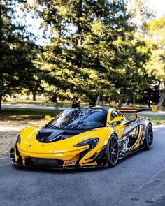 a yellow and black sports car parked on the side of a road in front of some trees