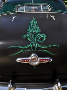 an old black car with green designs on it's hood