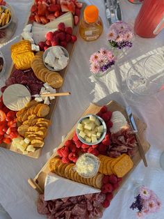 two wooden trays filled with different types of cheese and crackers on top of a white table cloth