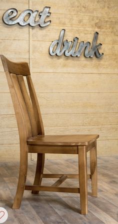 a wooden chair sitting in front of a wall with eat drink sign on it's side