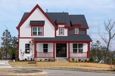 a red and white house with black roofing on the street in front of it