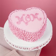 a heart shaped cake with the word mom on it sitting on top of a plate