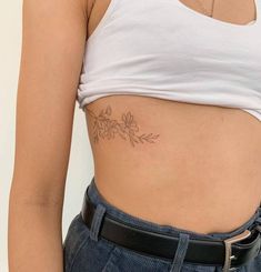 a woman's stomach with a flower tattoo on her left side ribcage