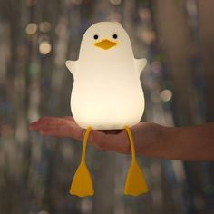 a hand holding a small light with a penguin on it