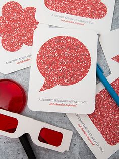 three red and white business cards sitting on top of each other next to a pair of glasses