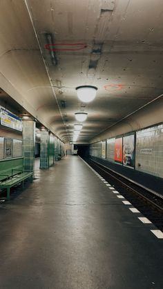 an empty subway station with green benches and signs on the side of the train tracks