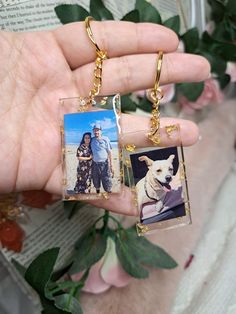 a person holding two pictures in their hands with flowers behind them and a dog on the other side